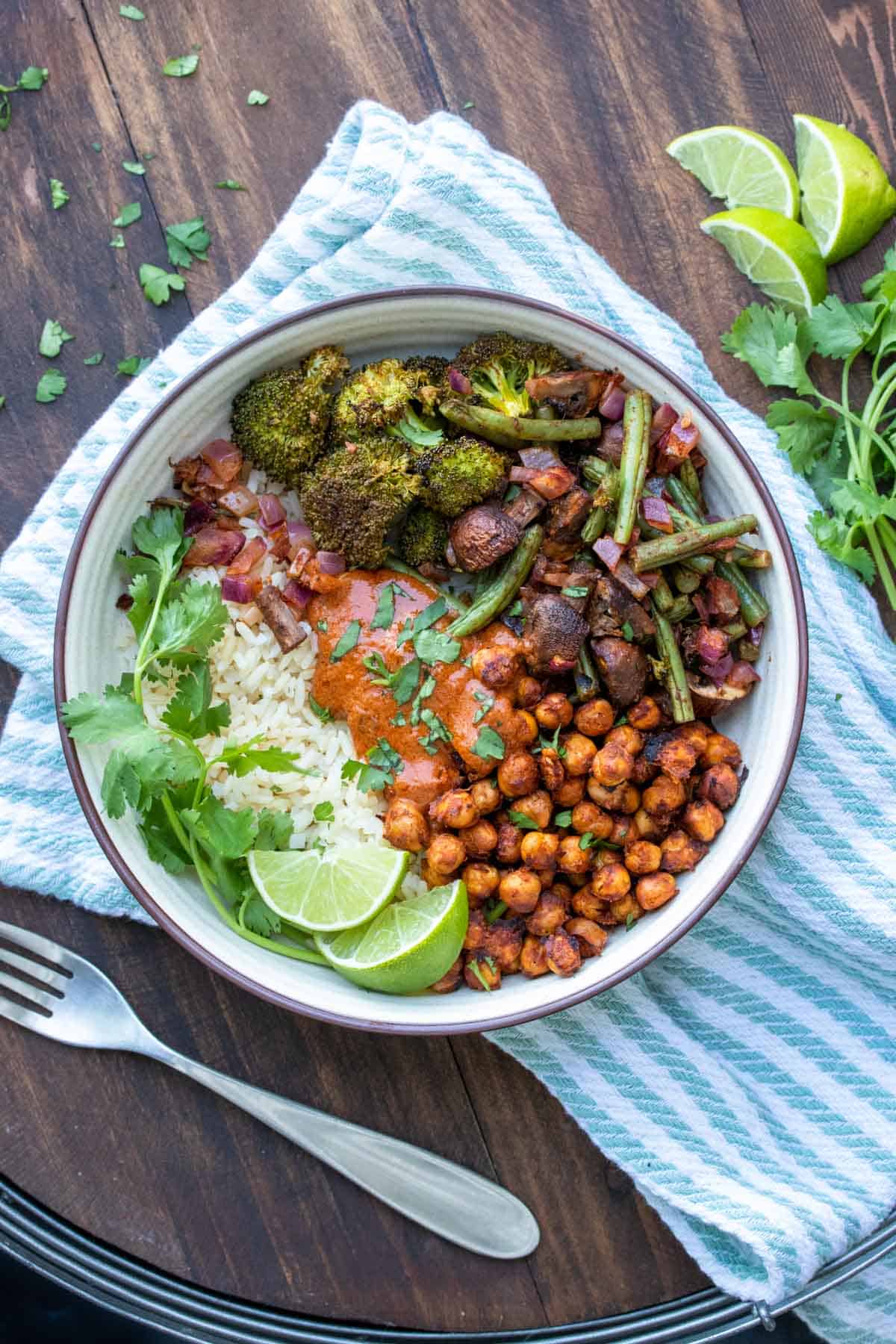 Bowl filled with roasted chickpeas and veggies over rice topped with tikka masala