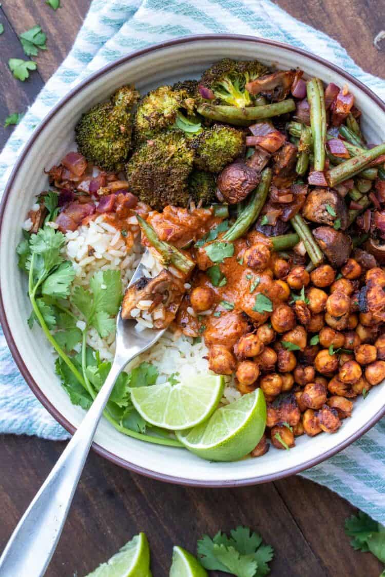 Fork getting a bite of rice with tikka masala sauce and roasted veggies and chickpeas