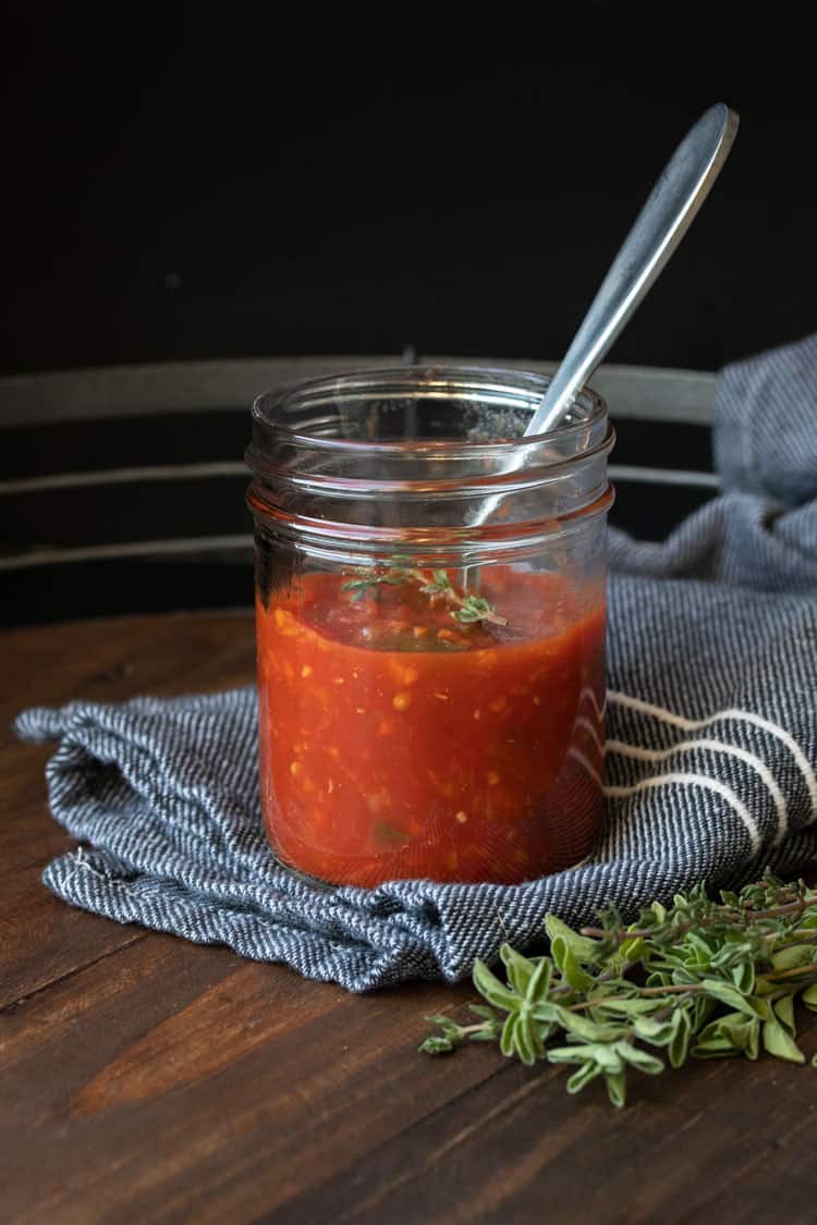 Glass jar with tomato sauce and a spoon in it