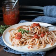 Spaghetti with tomato sauce on an off white plate