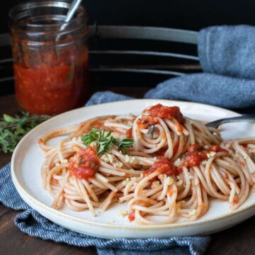 Spaghetti with tomato sauce on an off white plate