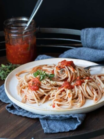 Spaghetti with tomato sauce on an off white plate