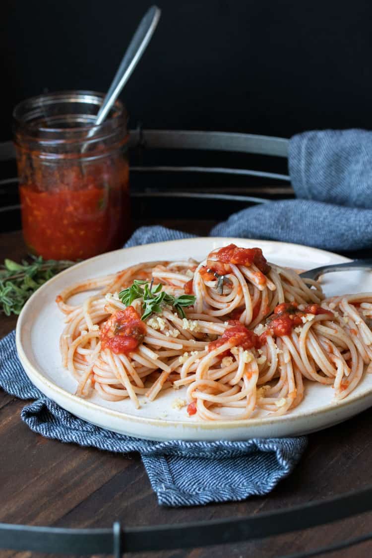 Spaghetti with tomato sauce on an off white plate