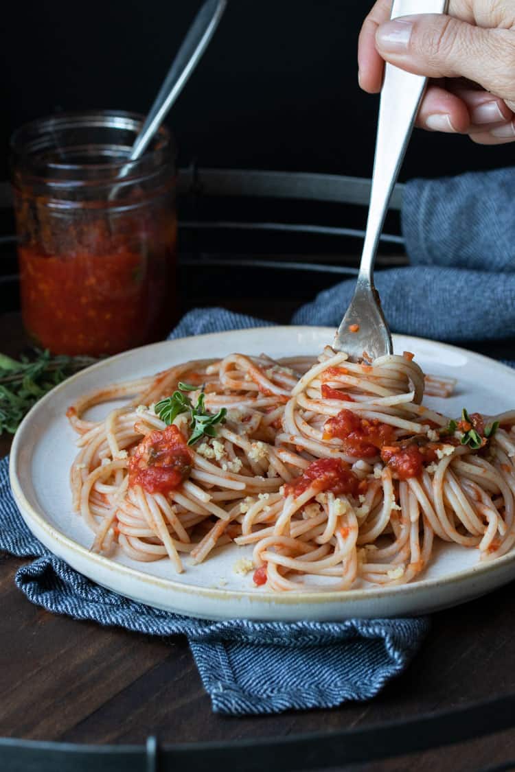 Fork twisting spaghetti around it from a plate of spaghetti