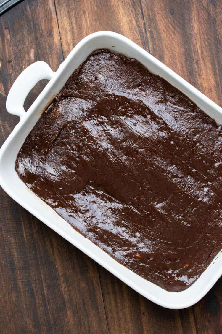 Brownie batter pressed into a white baking dish