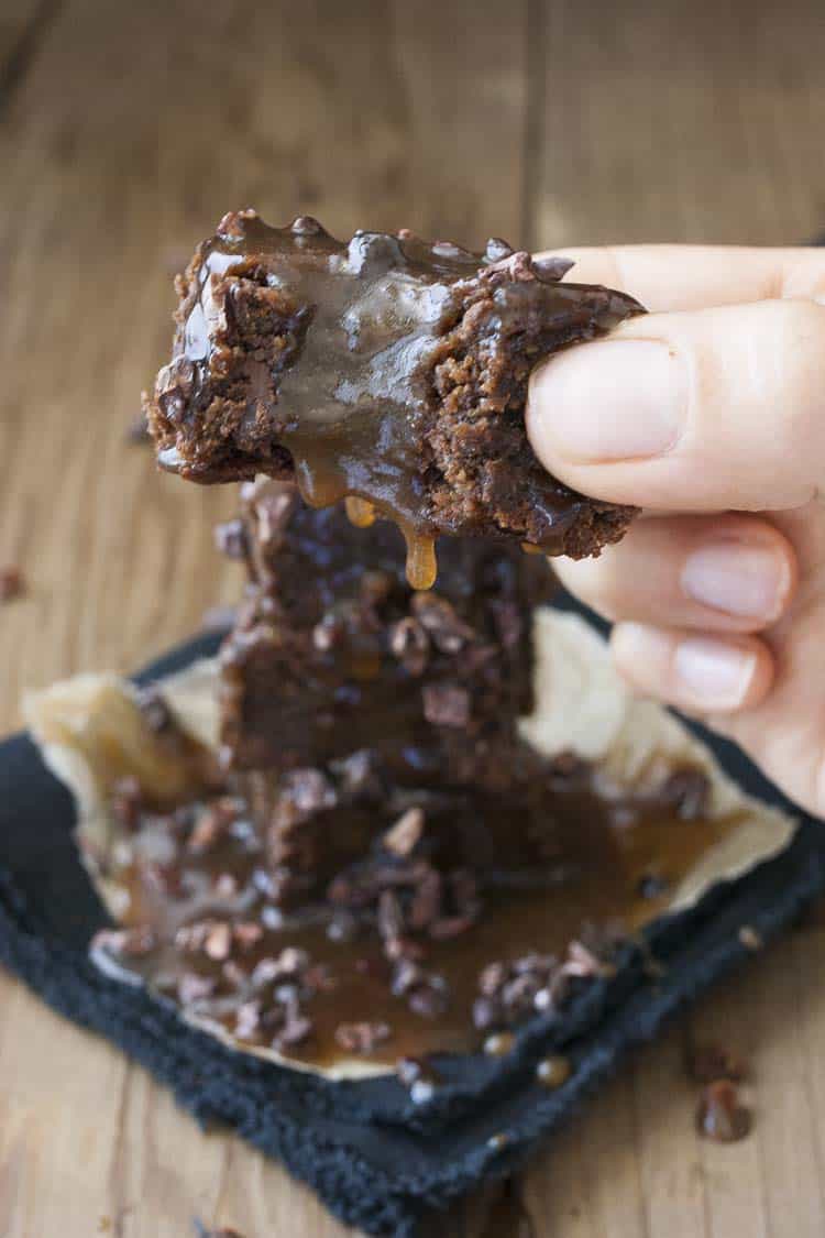 Hand holding a brownie with caramel with a bite out of it