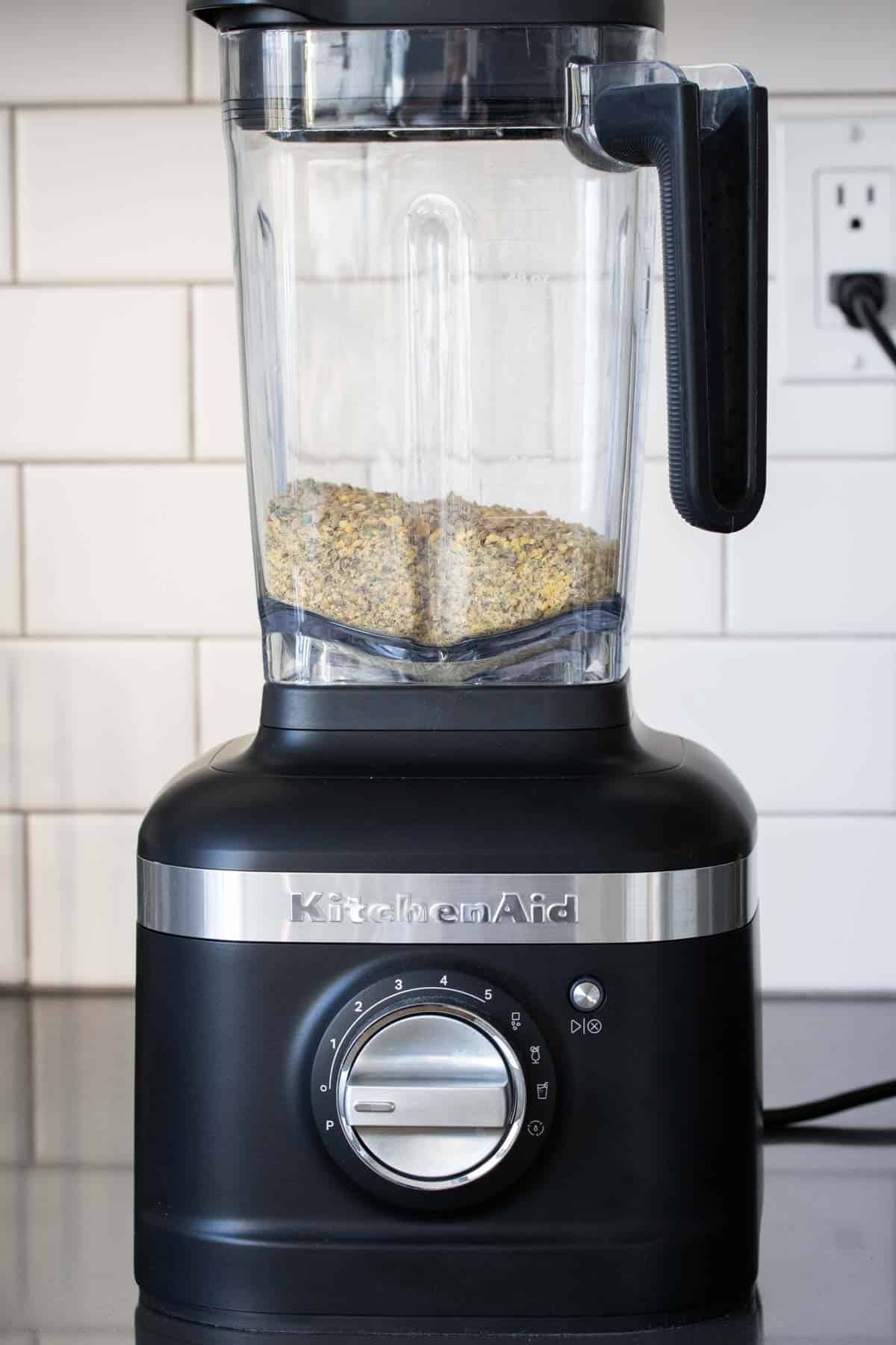 Black blender with dry lentils in it on a kitchen counter.