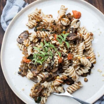 White plate with rotini pasta and lentil bolognese on it