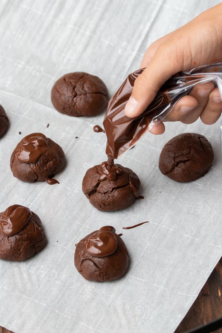 Hand putting melted chocolate on top of a brownie