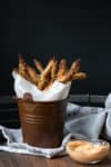 Brown bucket with parchment paper and breaded asparagus fries in it