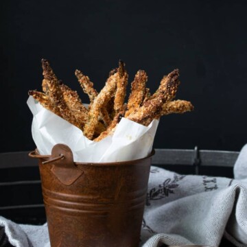 Brown bucket with parchment paper and breaded asparagus fries in it