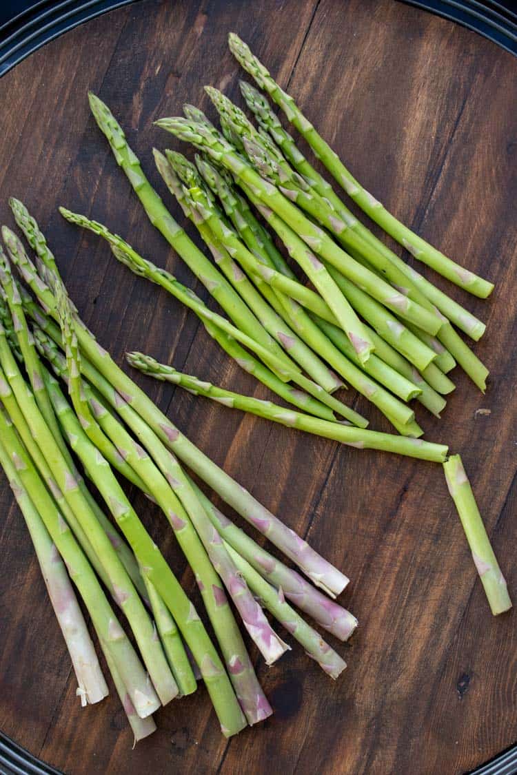 Piles of asparagus spears laying on a wooden surface