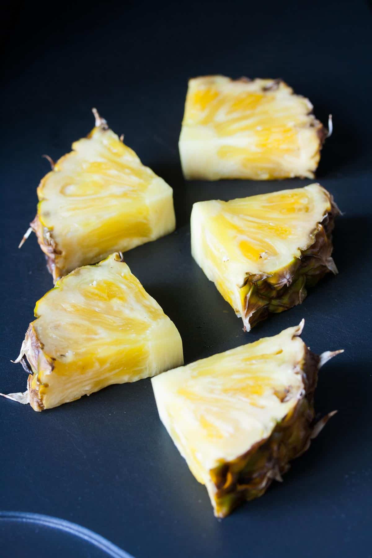 Slices of pineapple being grilled on a flat grill pan