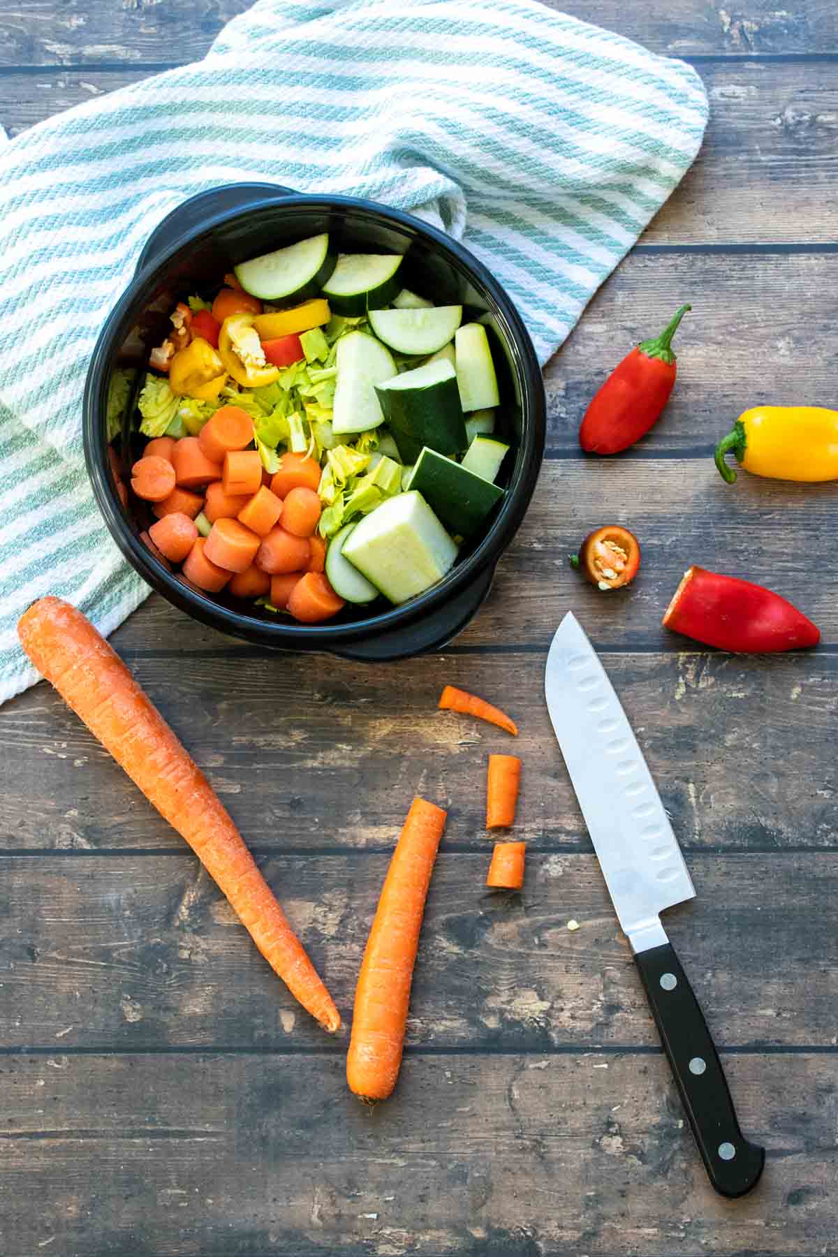 Knife next to veggies being chopped and put into a black container.
