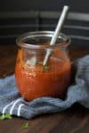 Glass jar with red enchilada sauce inside and a spoon in it