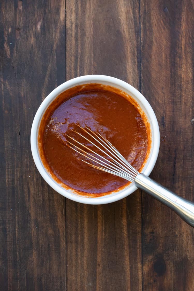 Top view of whisk mixing red enchilada sauce