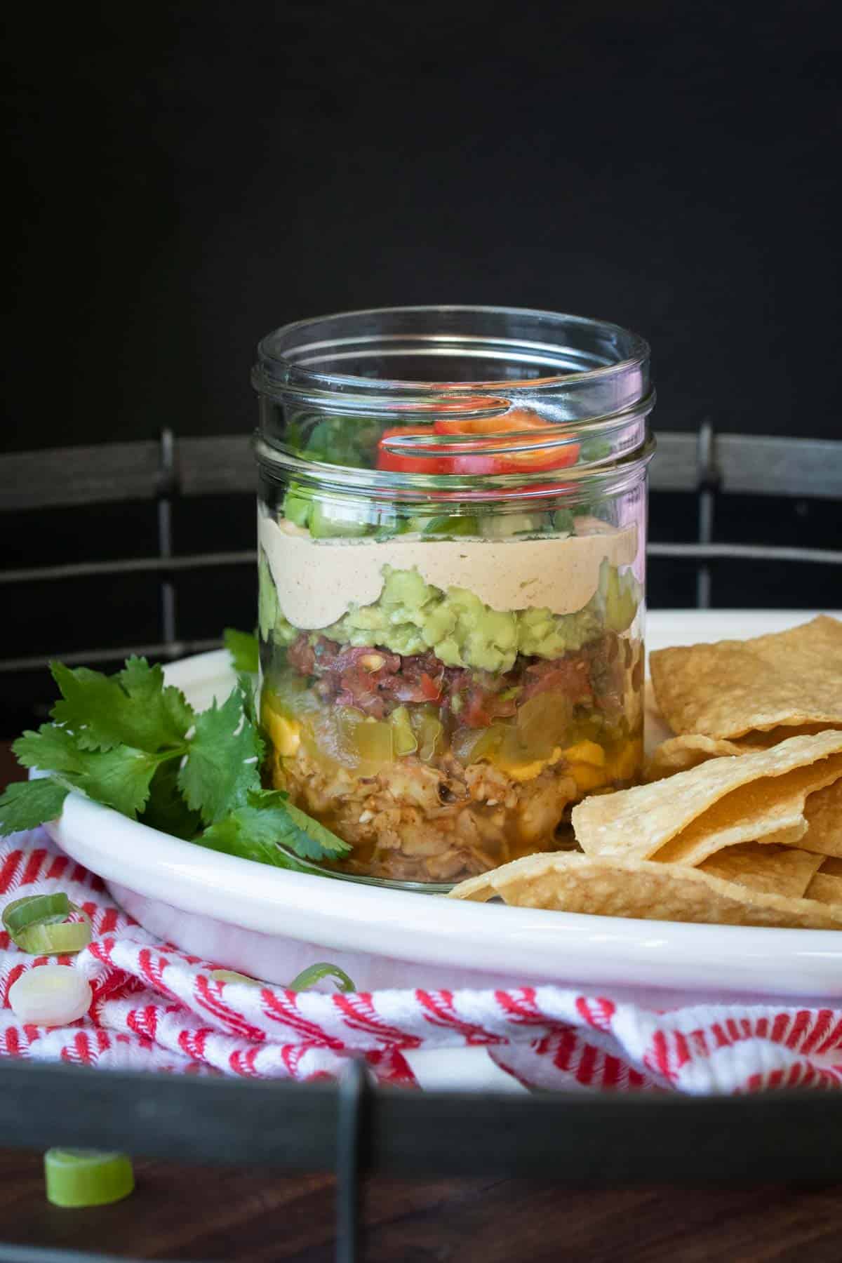 A glass jar filled with layers to make a 7 layer dip
