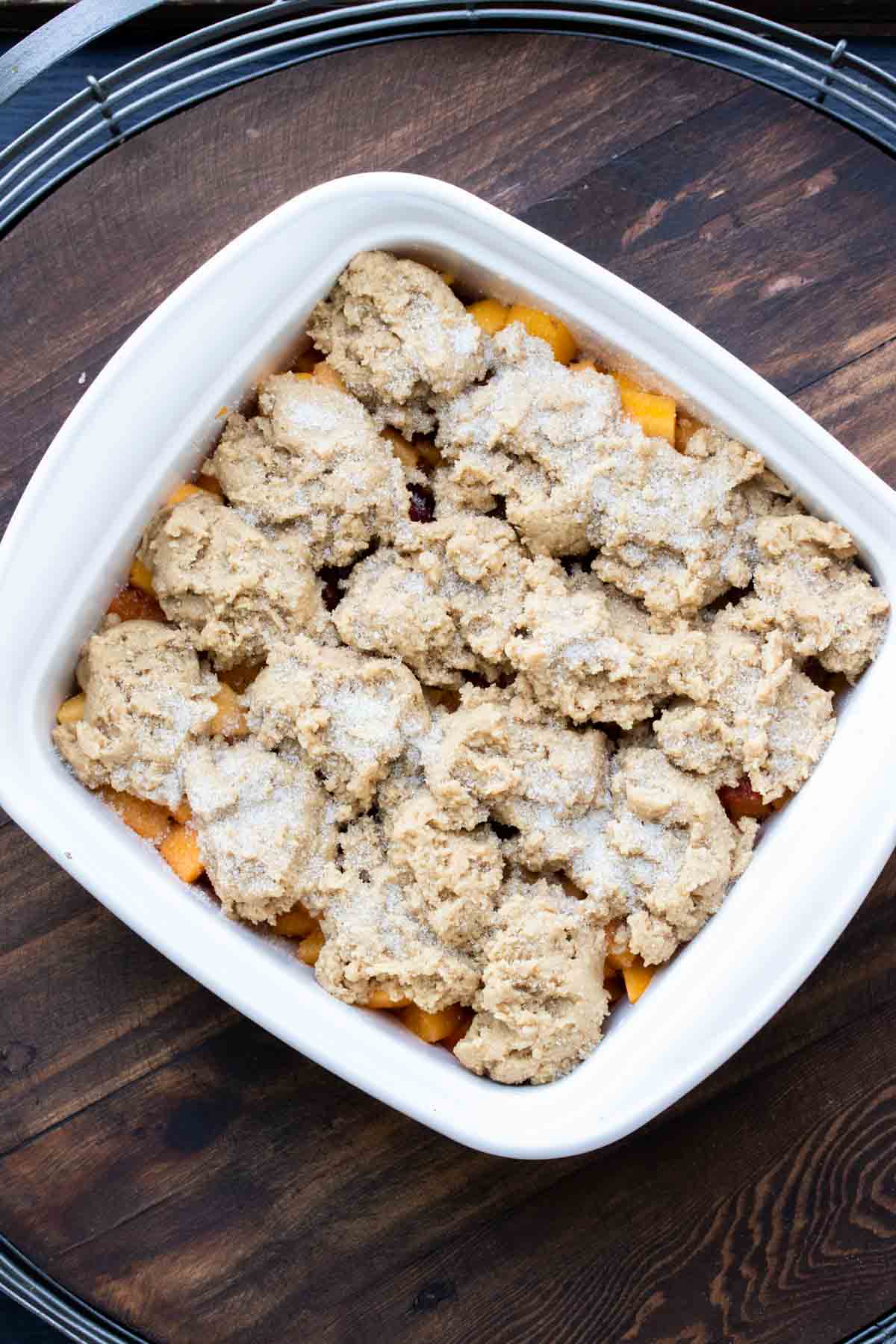 White baking dish filled with peach cobbler before it is baked.