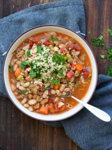 White bowl with pasta and vegetable bean soup inside.