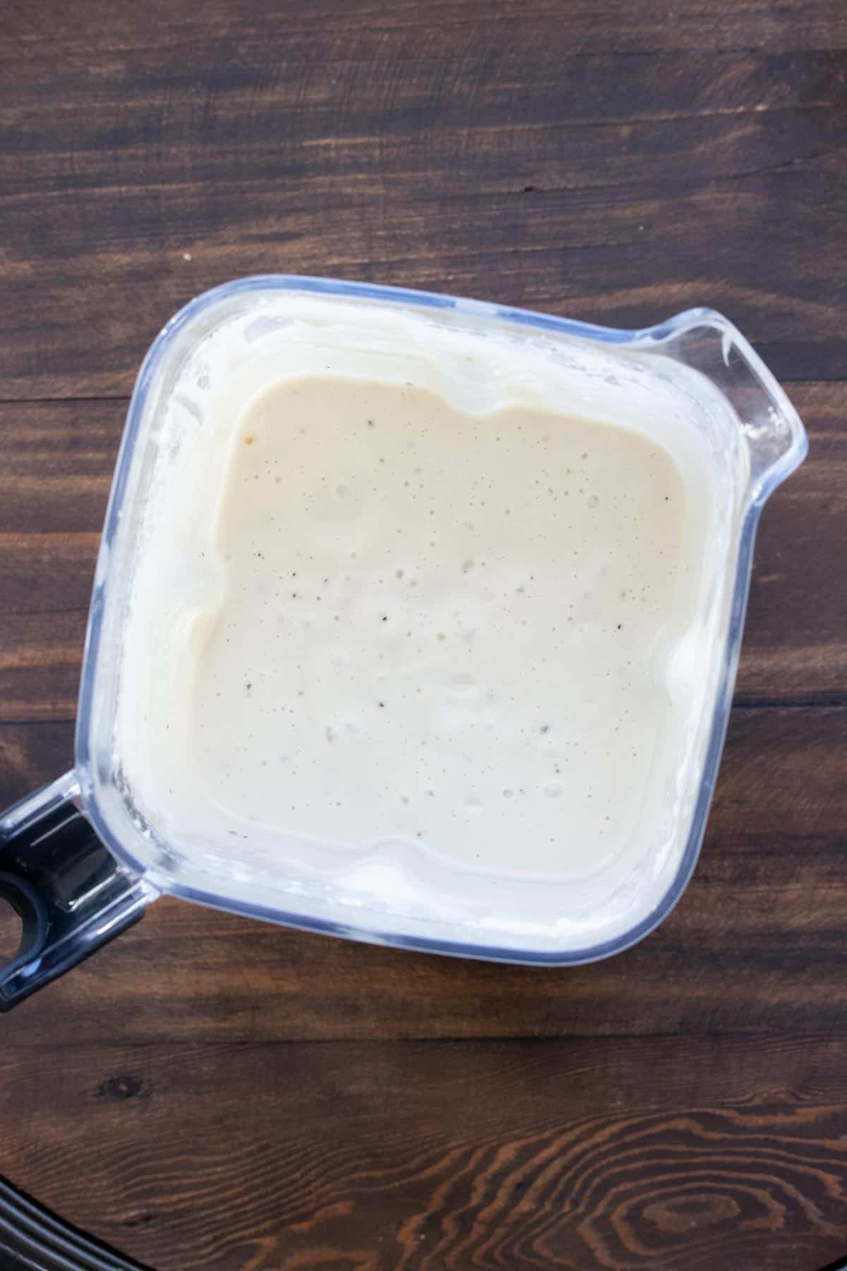 Top view of blender filled with white cheese sauce