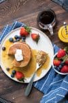 Top view of a stack of pancakes with maple syrup next to a bite of them on a fork