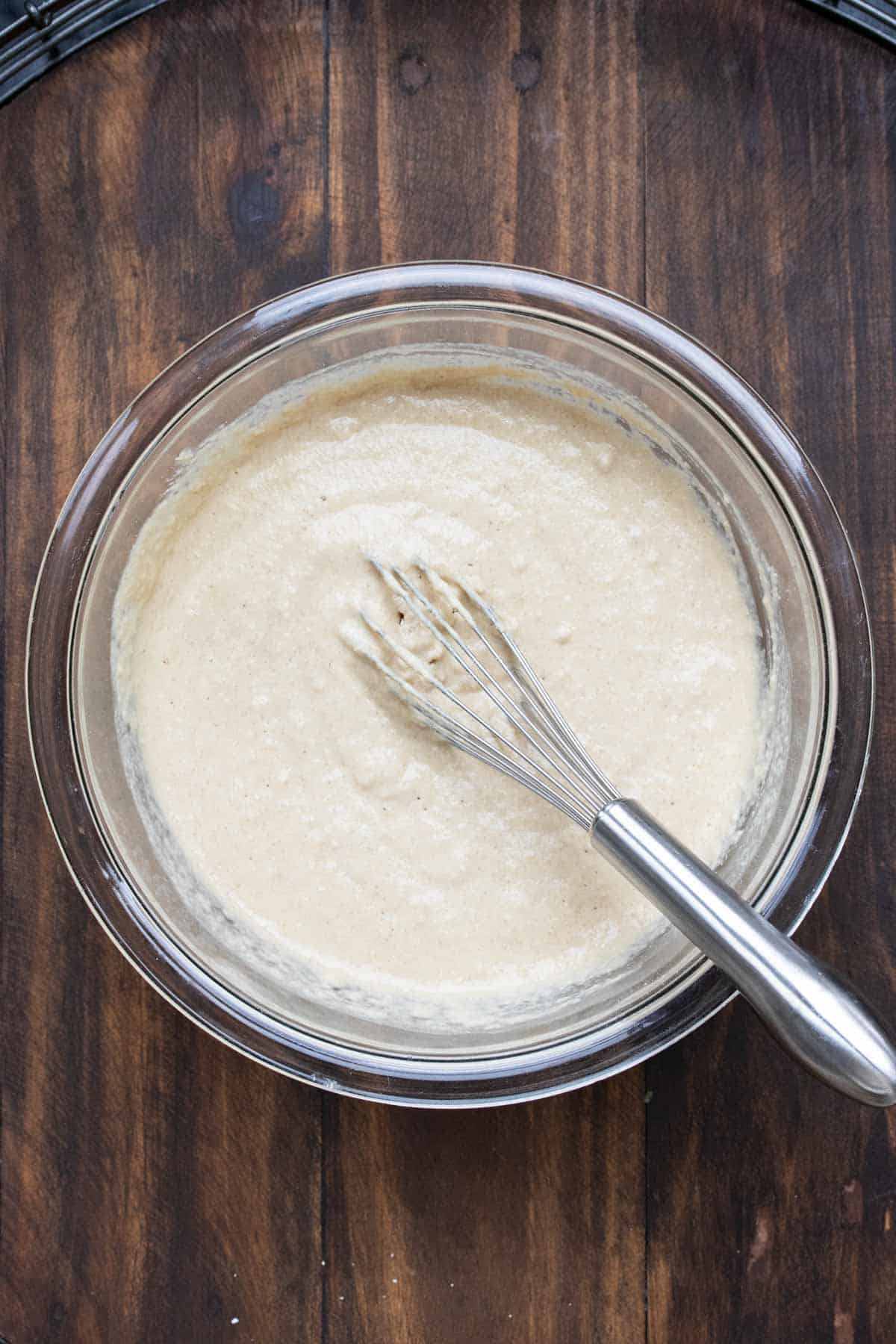 Whisk mixing pancake batter in a glass bowl