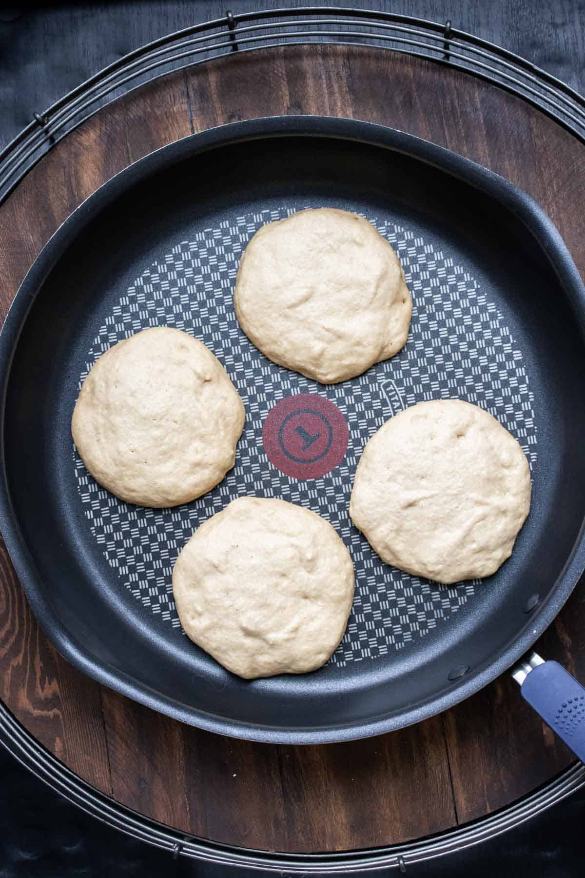 Frying pan with four pancakes being cooked in it