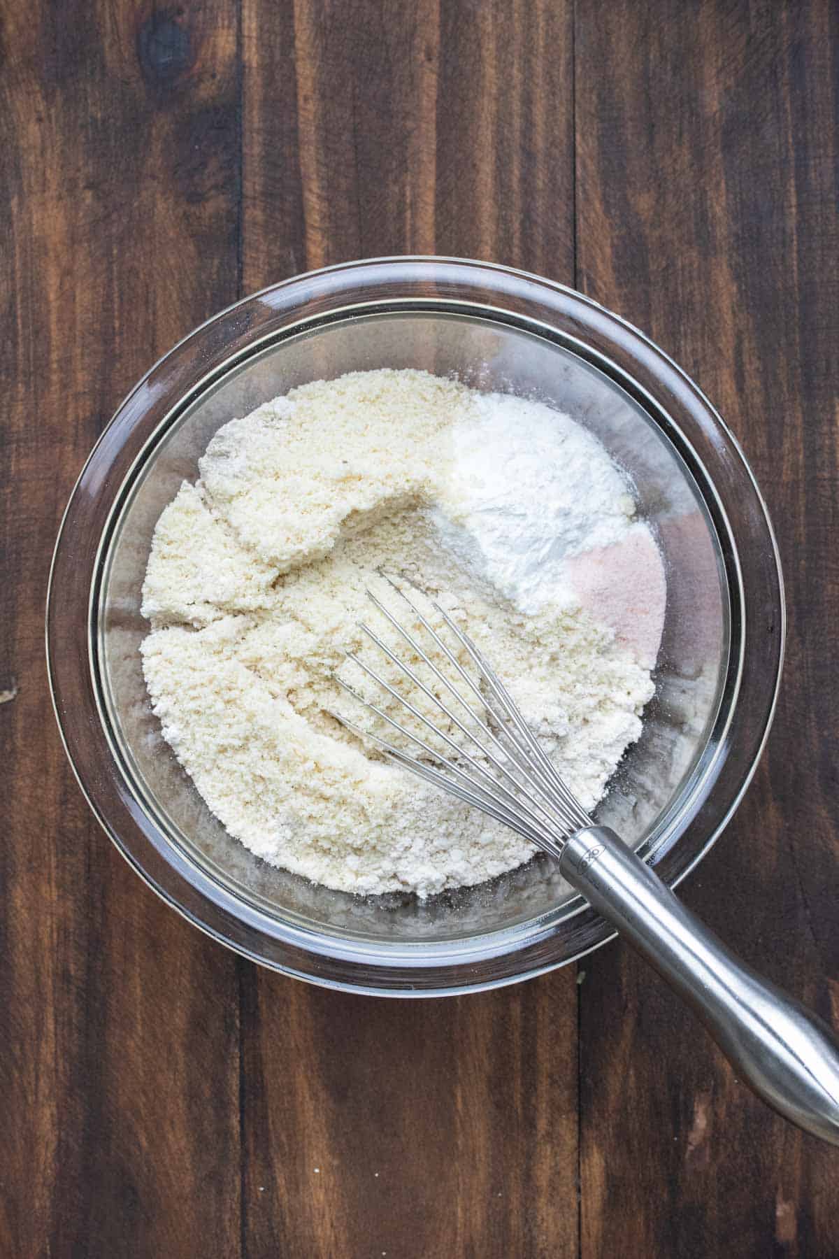 Glass bowl with dry pancake ingredients being mixed with a whisk