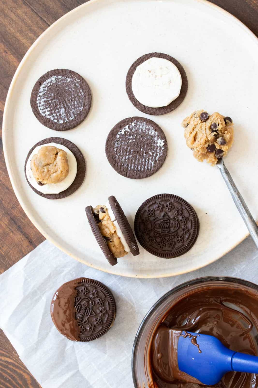 White plate with Oreos being opened and stuffed with cookie dough