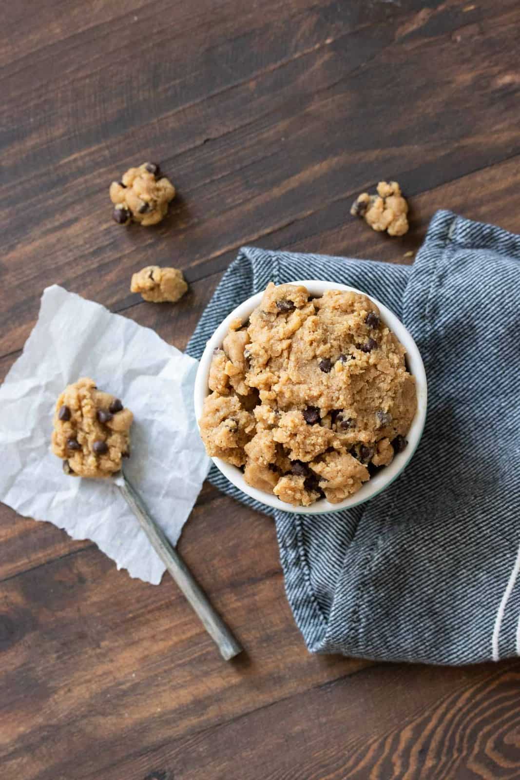 Top view of bowl of raw cookie dough next to spoonful of it