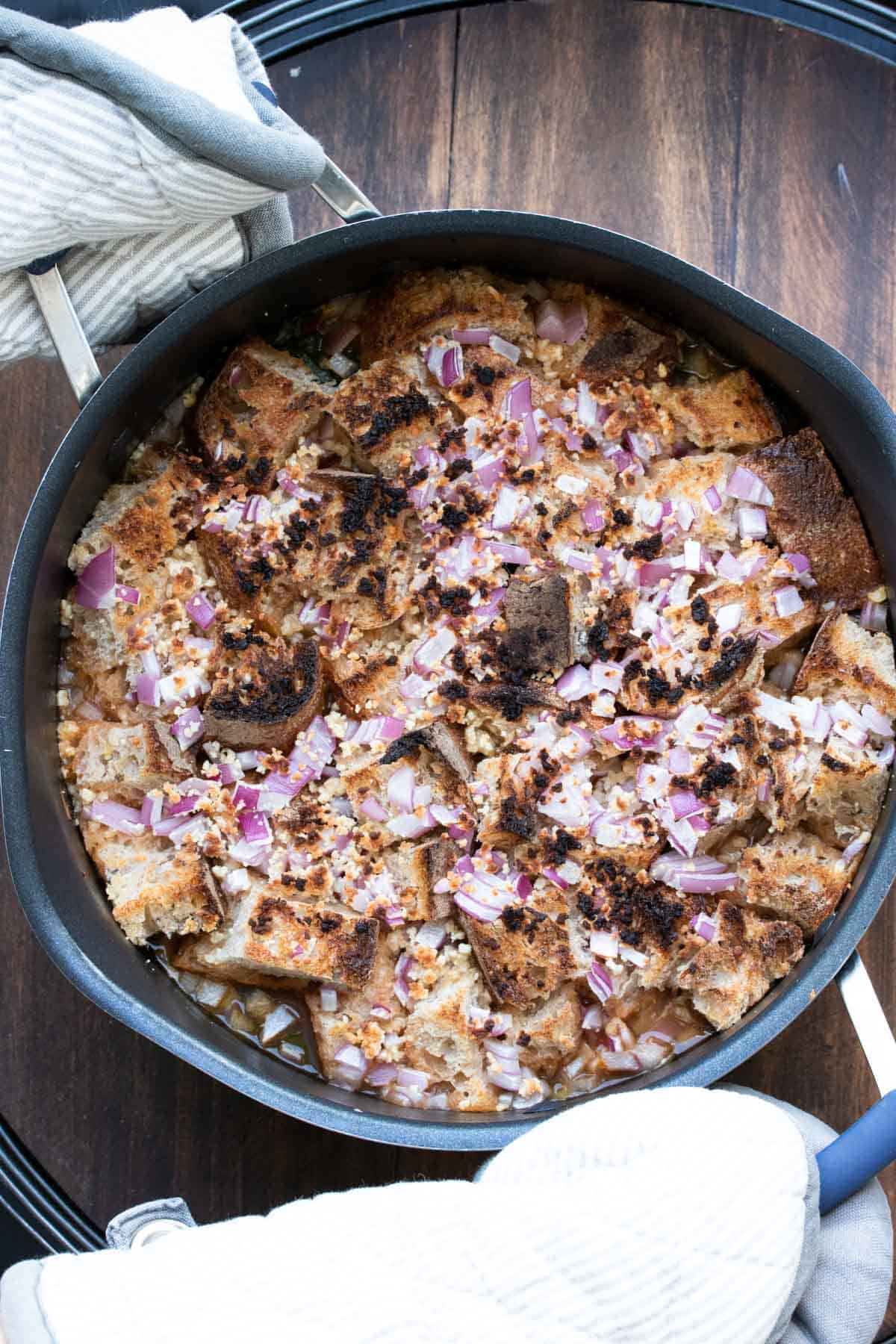 Crisp bread cubes with charred red onion on the top of soup in a pot