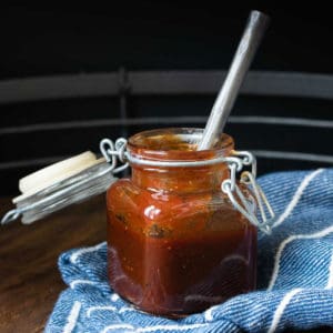 A silver spoon in a glass jar with a hinge with a rubber seal sitting on a blue towel.