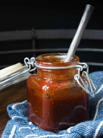 A silver spoon in a glass jar with a hinge with a rubber seal sitting on a blue towel.