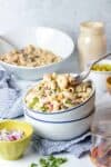 Two white bowls stacked and filled with classic macaroni salad