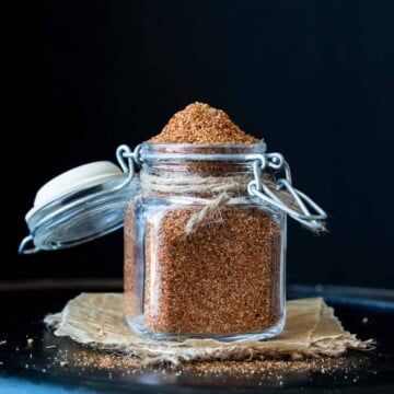 Front view of glass spice jar with clamp lid filled with homemade taco seasoning