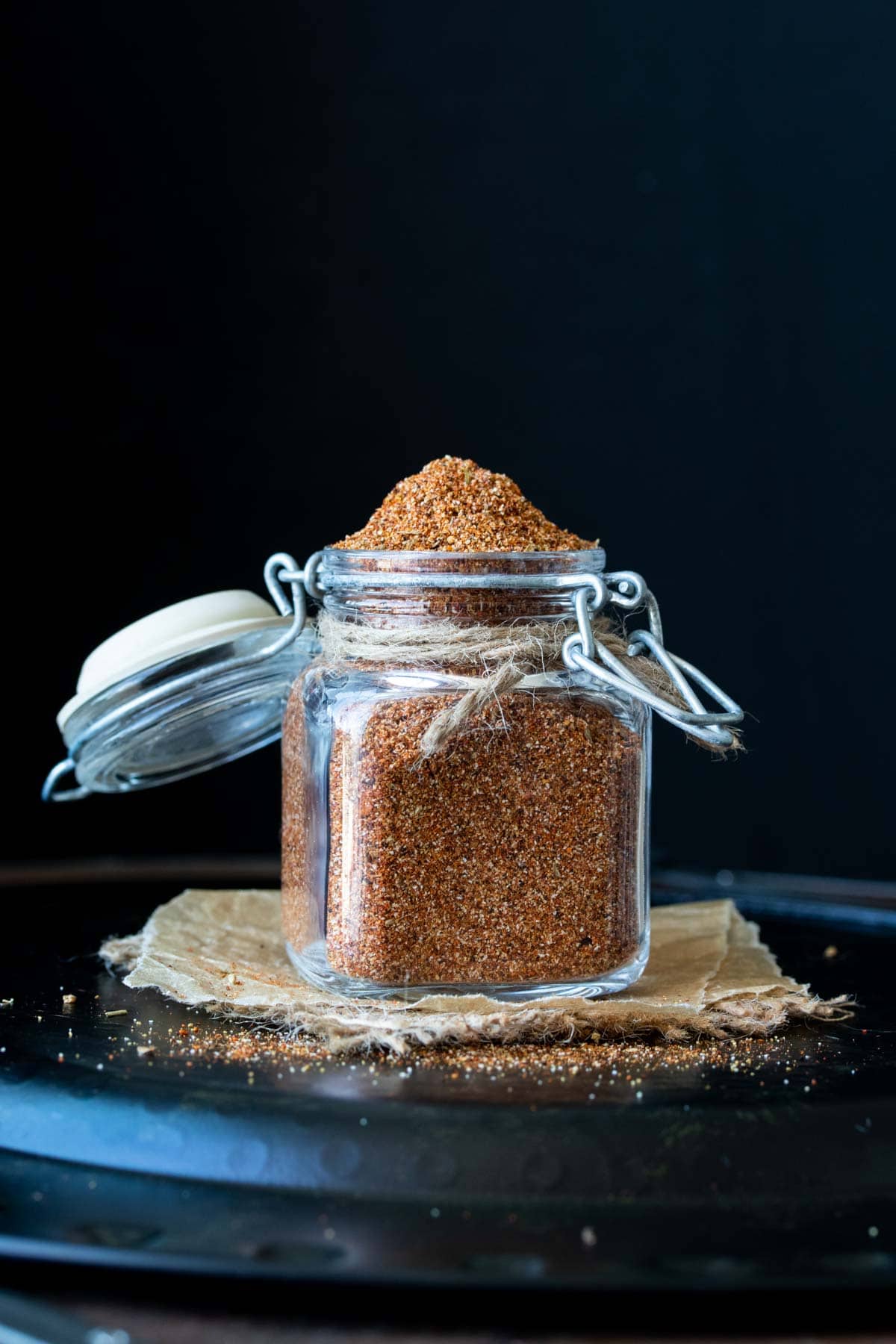Front view of glass spice jar with clamp lid filled with homemade taco seasoning