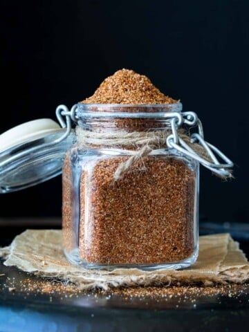 A glass jar with a flip top filled with taco seasoning