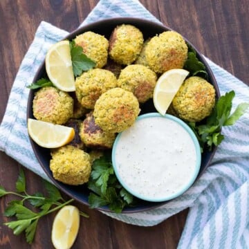 Black bowl filled with baked falafel and tahini dip