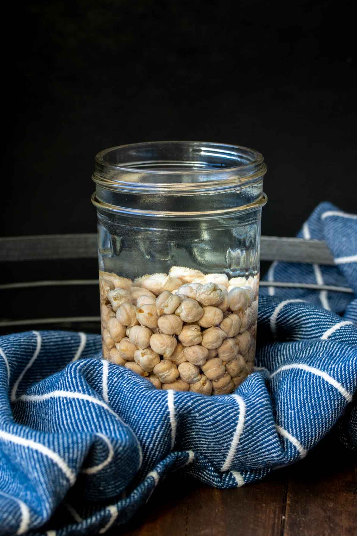 Glass jar with water and dried chickpeas inside
