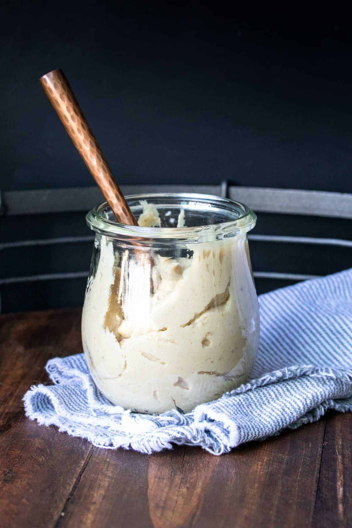 Copper spoon in a glass jar of cashew cream cheese.