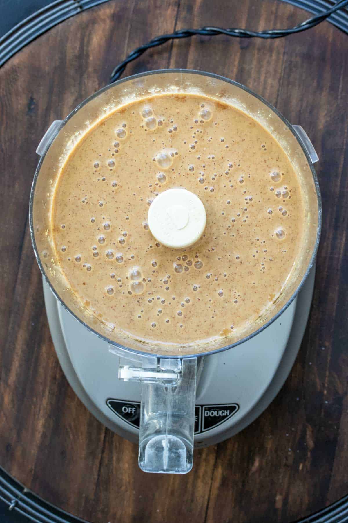 Top view of a food processor with a light brown mixture inside