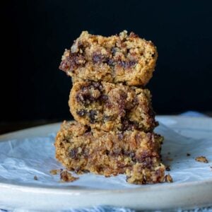 A white plate with a stack of three chocolate chip blondies on top.