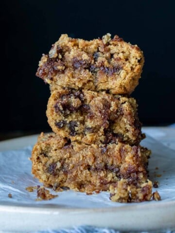 A white plate with a stack of three chocolate chip blondies on top.