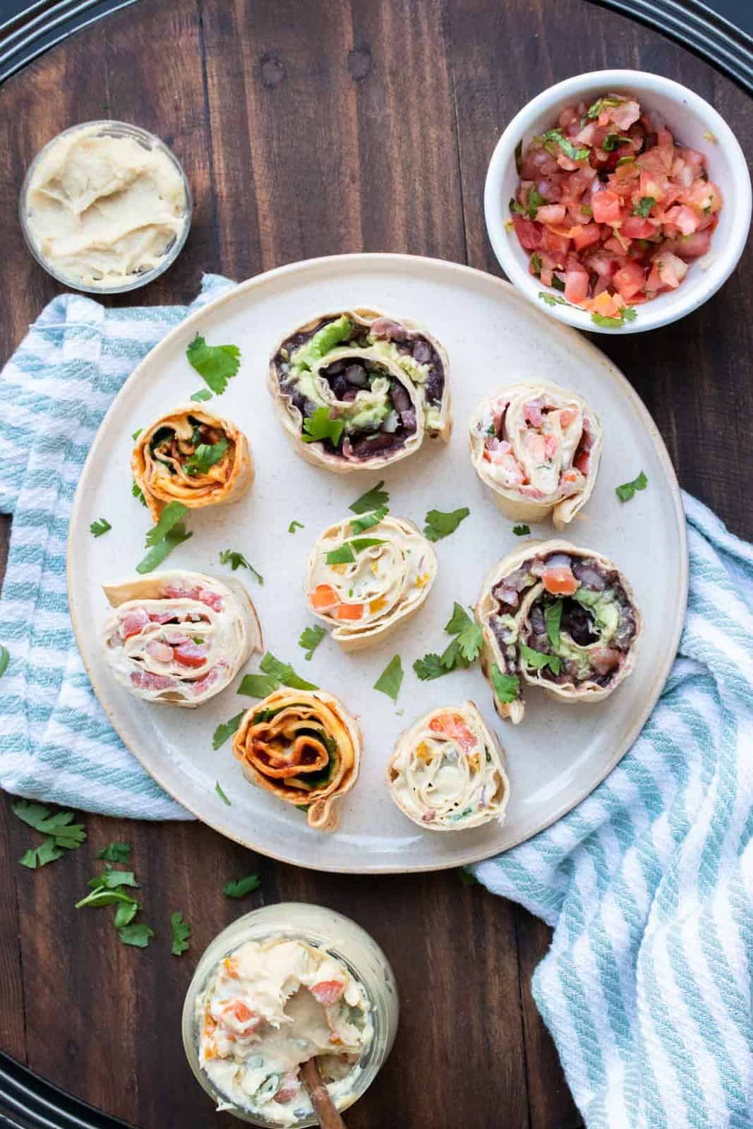 Cream plate with different types of pinwheel roll ups on it