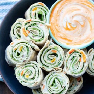 Black plate with pinwheel rolls ups filled with lettuce, salsa and cream cheese