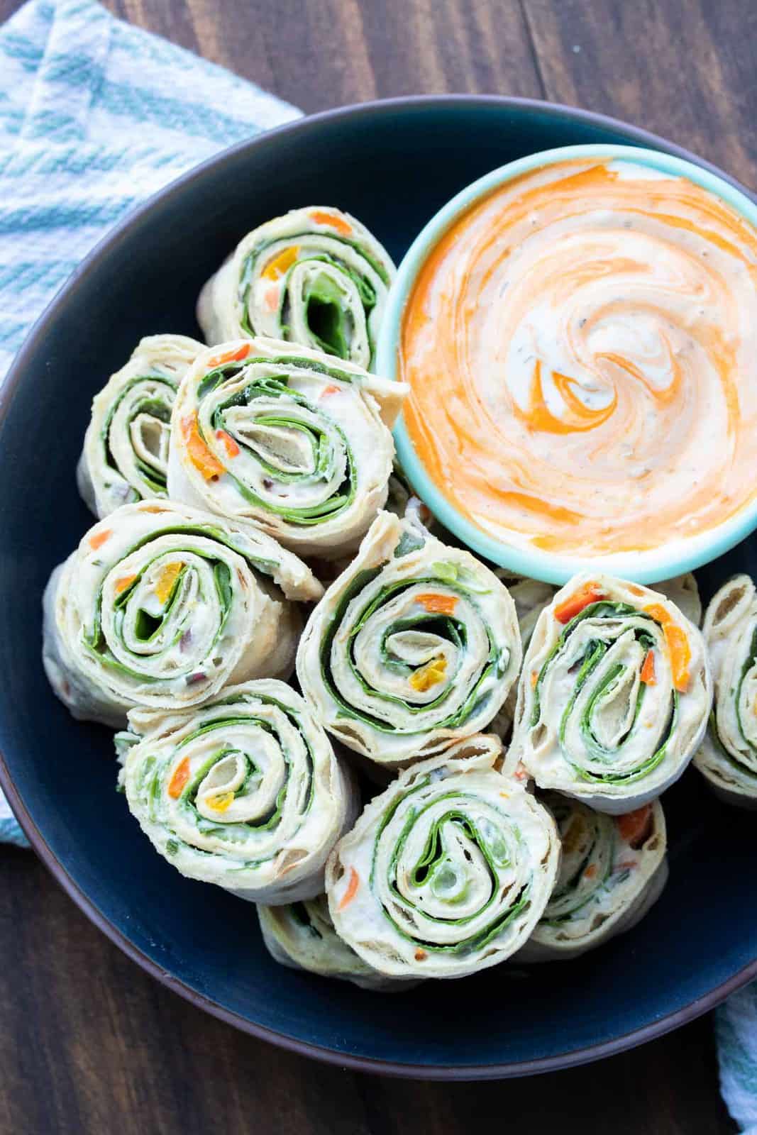 Black plate with pinwheel rolls ups filled with lettuce, salsa and cream cheese