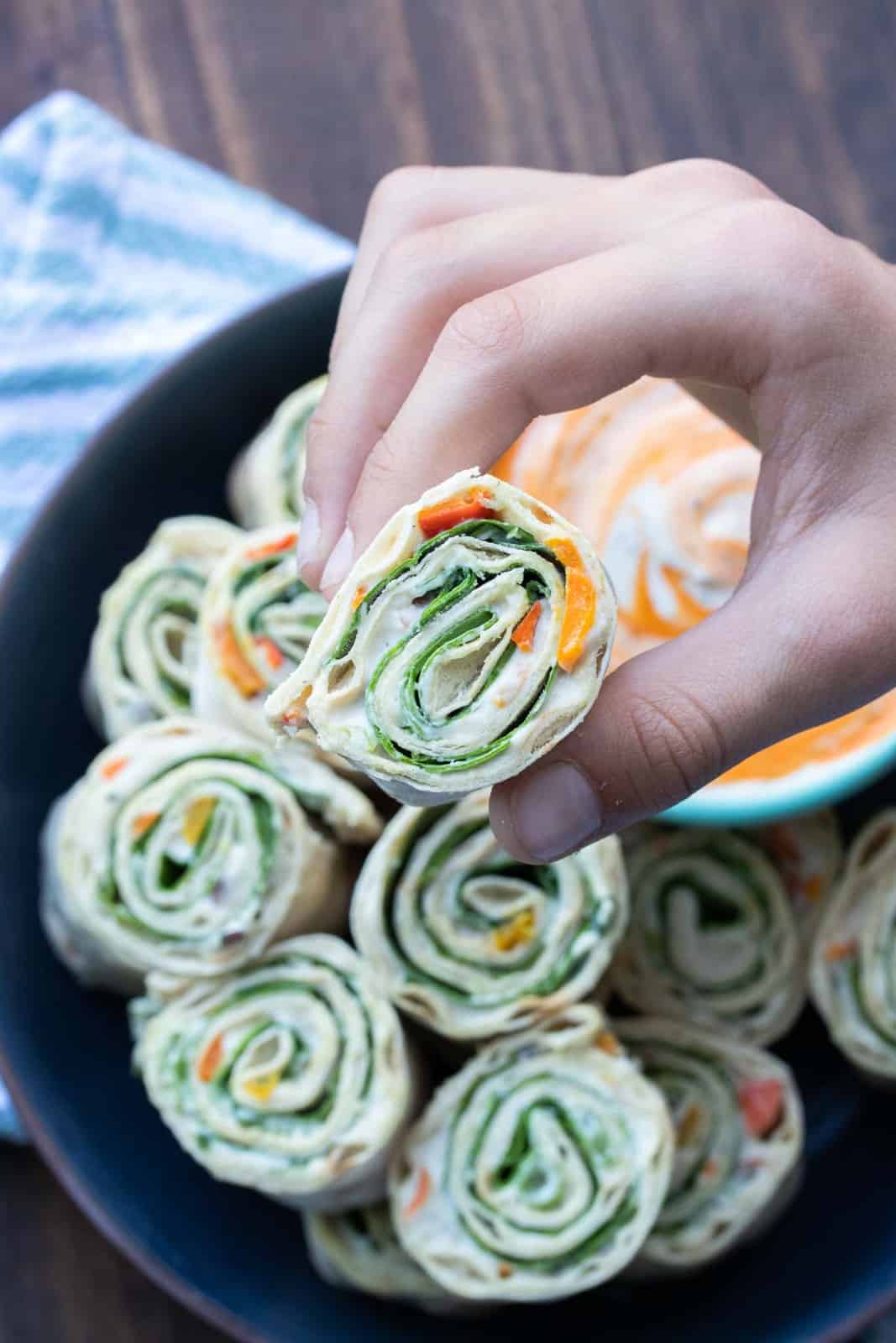 Hand picking up a lettuce, salsa and cream cheese pinwheel sandwich