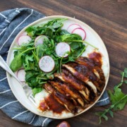 White plate with sliced grilled portobello mushroom and a side of sautéed greens