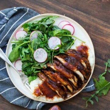 White plate with sliced grilled portobello mushroom and a side of sautéed greens