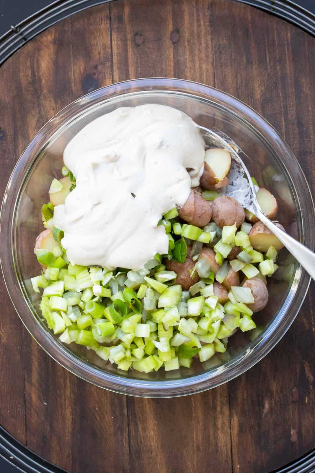 Spoon mixing ingredients together for creamy potato salad